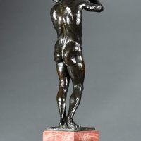 Alt text: Bronze sculpture of a nude figure holding a rock above his head