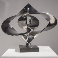 Alt text: Polished bronze sculpture of large distorted circles interlocked