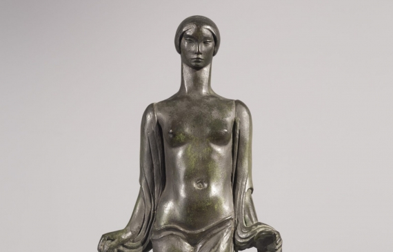 Alt text: Art Deco sculpture of a topless woman with fabric draped around her arms and torso