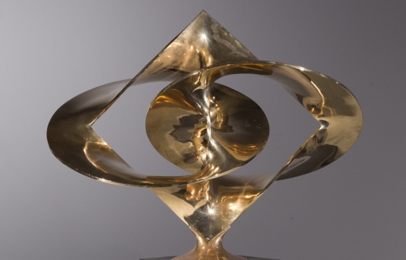 Alt text: Polished bronze sculpture of large distorted circles interlocked