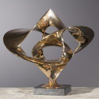 Alt text: Polished bronze sculpture of large distorted circles interlocked