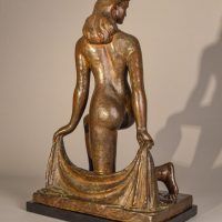 Alt text: Bronze sculpture of a nude dancer kneeling with one leg on the ground, holding a shawl behind her, angled view