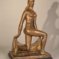 Alt text: Bronze sculpture of a nude dancer kneeling with one leg on the ground, holding a shawl behind her, angled view