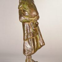Alt text: Bronze sculpture of a young woman carrying her baby in 1910s clothing, side view