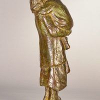 Alt text: Bronze sculpture of a young woman carrying her baby in 1910s clothing, angled view