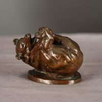 Alt text: Bronze sculpture of a bear on his back holding his feet