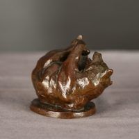 Alt text: Bronze sculpture of a bear on his back holding his feet