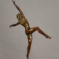 Alt text: Bronze sculpture of a nude woman posing with arms outstretched in an L shape and right leg lifted with knee bent