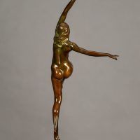 Alt text: Bronze sculpture of a nude woman posing with arms outstretched in an L shape and right leg lifted with knee bent