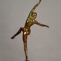 Alt text: Bronze sculpture of a nude woman posing with arms outstretched in an L shape and right leg lifted with knee bent