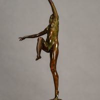 Alt text: Bronze sculpture of a nude woman posing with arms outstretched in an L shape and right leg lifted with knee bent