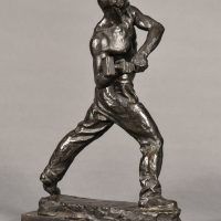 Alt text: Bronze sculpture of a muscular shirtless man swinging a hammer