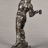 Alt text: Bronze sculpture of a muscular shirtless man swinging a hammer