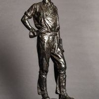 Alt text: Bronze sculpture of a telephone linesman in work gear