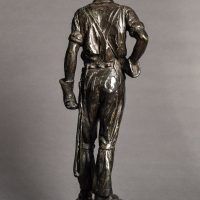 Alt text: Bronze sculpture of a telephone linesman in work gear