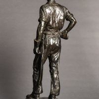 Alt text: Bronze sculpture of a telephone linesman in work gear