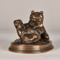Alt text: Bronze sculpture of a bear lying on his back with feet up, angled view