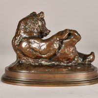 Alt text: Bronze sculpture of a bear lying on his back with feet up, side view