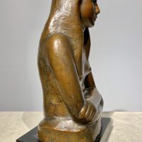 Alt text: Bronze sculpture of a girl with crossed arms, side view