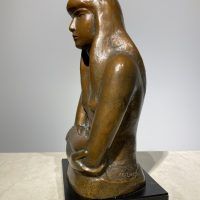 Alt text: Bronze sculpture of a girl with crossed arms, side view