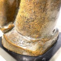 Alt text: Bronze sculpture of a girl with crossed arms, angled view