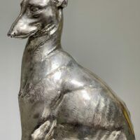 Alt text: Silvered bronze sculpture of a seated dog