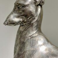 Alt text: Silvered bronze sculpture of a seated dog