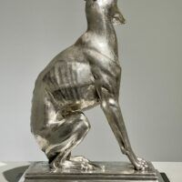 Alt text: Silvered bronze sculpture of a seated dog