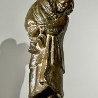 Alt text: Bronze sculpture of a young woman carrying her baby in 1910s clothing