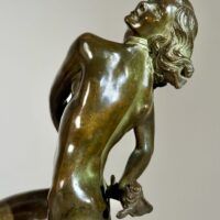 Alt text: Bronze sculpture of a nude woman skipping and holding a fish in one hand