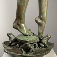 Alt text: Bronze sculpture, detail of two feet among frogs