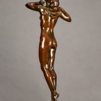 Alt text: Bronze sculpture of a nude woman standing with elbows out and hands framing her face