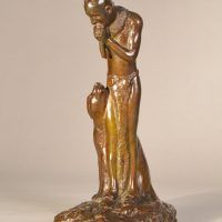 Alt text: Bronze sculpture of a Native American man playing flute, looking down at a Puma sitting beside him, side view