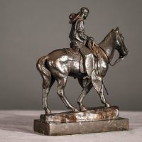 Alt text: Bronze sculpture of a cowboy riding on a horse