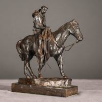 Alt text: Bronze sculpture of a cowboy riding on a horse