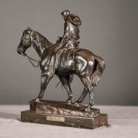 Alt text: Bronze sculpture of a cowboy riding on a horse