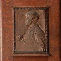 Alt text: Bronze bas relief of Jules Bastian LePage with paintbrush and palette