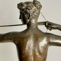 Alt text: Bronze sculpture of a woman holding a bow and arrow, detail