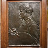 Alt text: Bronze bas relief of a man in profile with a paintbrush and palette