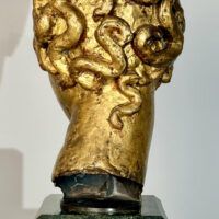 Alt text: Stylized, gilt bronze sculpture of a head of a boy with curly hair