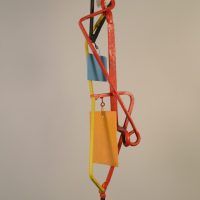 Alt text: Abstract kinetic sculpture of painted welded steel with three hanging/movable pieces, side view