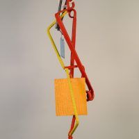 Alt text: Abstract kinetic sculpture of painted welded steel with three hanging/movable pieces, side view