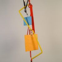 Alt text: Abstract kinetic sculpture of painted welded steel with three hanging/movable pieces, rear view