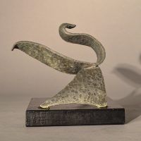 Alt text: Abstract soldered lead sculpture atop a wooden base resembling a swan, side view
