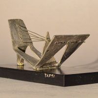 Alt text: Abstract soldered lead sculpture atop a wooden base resembling a drawbridge, angled view