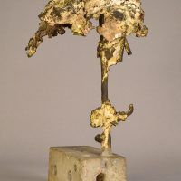 Alt text: Welded bronze sculpture shaped like a tree mounted on a slag block, angled view