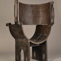 Alt text: Steel sculpture in the shape of a small chair with rounded seat, angled view