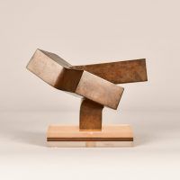 Alt text: Abstract steel sculpture with three blocky sections atop a base