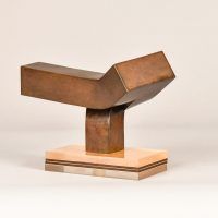 Alt text: Abstract steel sculpture with three blocky sections atop a base