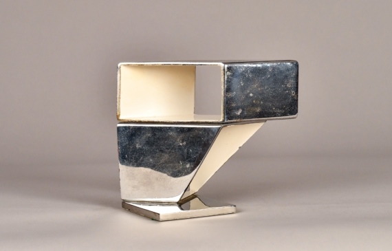 Alt text: Abstract sculpture made of steel and enamel with two geometric shapes fused together